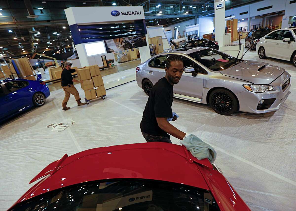 Anthony Brown puts a shine on a vehicle in the Subaru booth during the setup at the Houston Auto Show at NRG Center.
