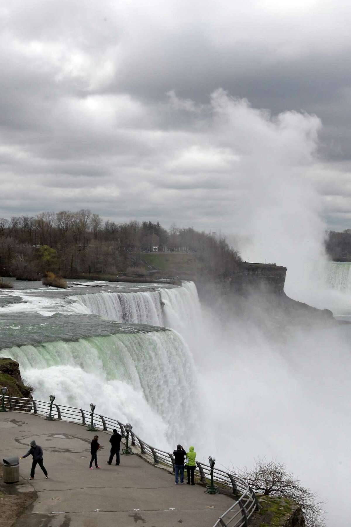 FILE--In this April 11, 2012 file photo, tourists visit the American Falls in Niagara Falls, N.Y. New York officials are considering temporarily turning Niagara Falls into a trickle. State officials are holding a public hearing this week to discuss plans for replacing 115-year-old bridges linking the mainland to islands near the brink of Niagara Falls. To do so, they might reduce the flow on the American side of the falls by building a temporary structure to redirect Niagara River water to the Canadian side. (AP Photo/David Duprey, File) ORG XMIT: NYMG103