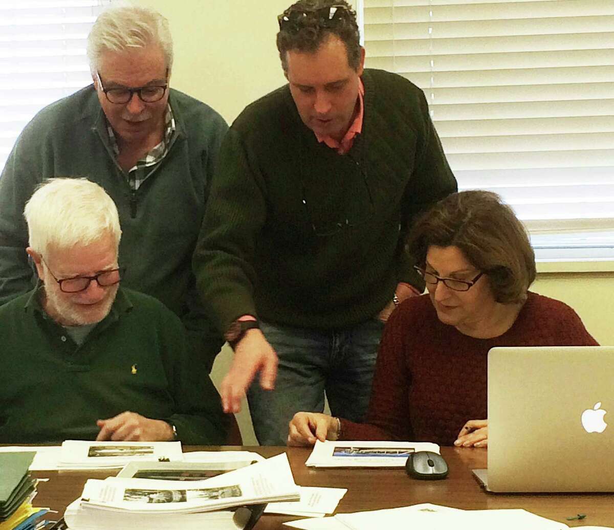 Members of the Saugatuck Swing Bridge Study Subcommittee -- Robert Weingarten, Peter Fullbright, Morley Boyd and Janet Rubel look at pictures of the span -- met to discuss finishing touches on their report that wiill recommend designating the span a local historic landmark.