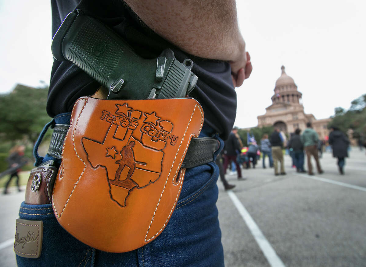 In a Friday, Jan. 1, 2016 photo, Terry Holcomb, Executive Director of Texas Carry happily displays his customized holster as he walks to the Capitol for a rally. Open Carry Texas and Texas Carry held a rally on the south steps of the Texas State Capitol in Austin to celebrate Texas becoming an open carry state. President Barack Obama defended his administration's plans to tighten the nation's gun-control restrictions without going through Congress, insisting Jan. 4 that the steps he'll announce fall within his legal authority and uphold the constitutional right to own a gun. (Ralph Barrera/Austin American-Statesman via AP) AUSTIN CHRONICLE OUT, COMMUNITY IMPACT OUT, INTERNET AND TV MUST CREDIT PHOTOGRAPHER AND STATESMAN.COM, MAGS OUT; MANDATORY CREDIT