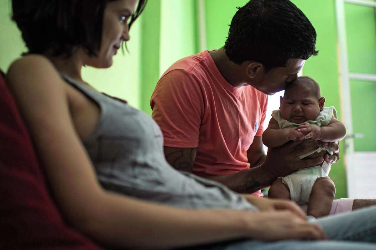 Matheus Lima, 22, (C) and Kleisse Marcelina,24, are seen at home with their son Pietro, 2 month, suffering from microcephalia caught through an Aedes Aegypti mosquito bite, in Salvador, Brazil on January 28 , 2016. AFP PHOTO / Christophe SIMONCHRISTOPHE SIMON/AFP/Getty Images