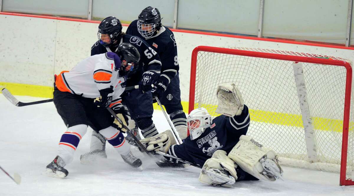 Staples-Weston-Shelton goalie Zach Bloom makes a save as Stamford-Westhill’s Chris Clemmenson crashes the net during Saturday’s game at Terry Conners Rink.