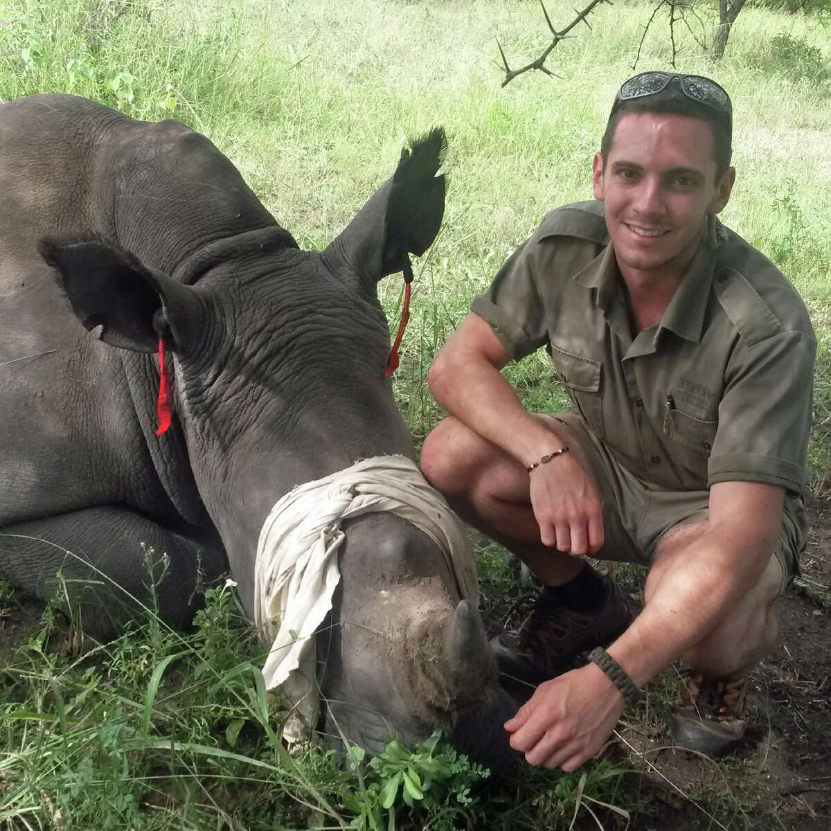 Greenwich native Axel Hunnicutt poses with an 18-month-old white rhino after placing microchips in his horns.