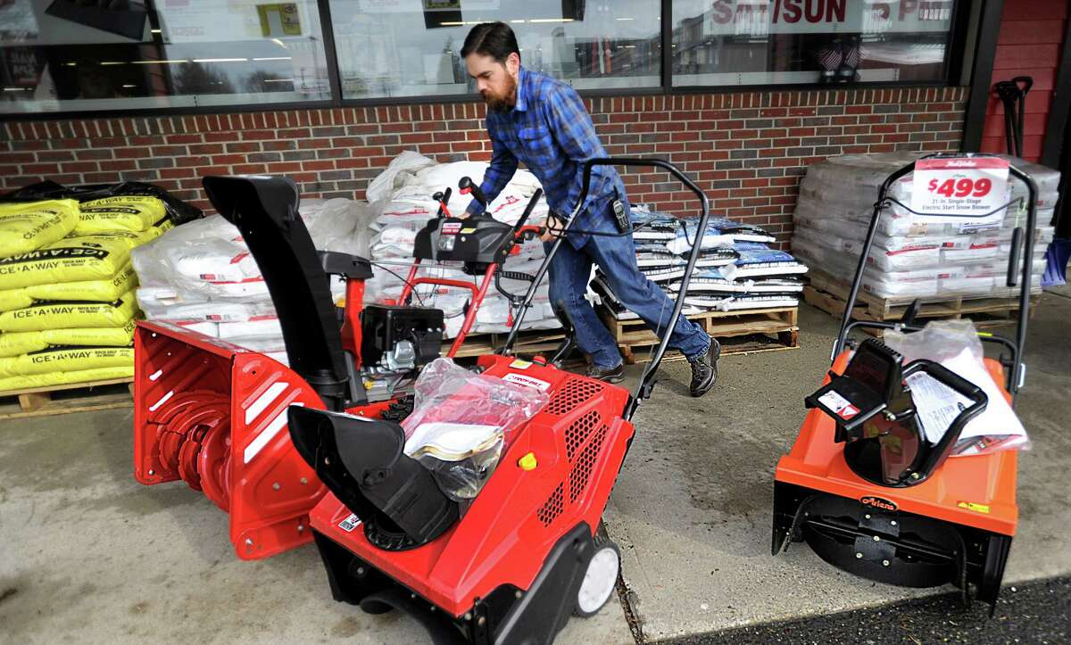 Ryan Clifford, an owner of True Value Hardware in Bethel, moves snowblowers into their display spot outside after the Dolan Plaza store Thursday, February 4, 2016. He moved them out of the rain earlier. True Value has a full supply of shovels, salt and sand due to a mild winter, Thursday, Feb. 4, 2016.