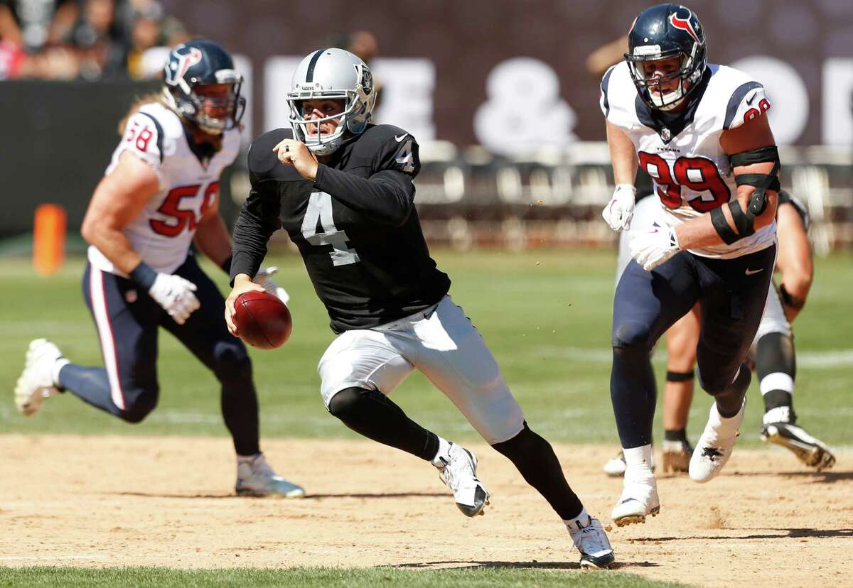 Oakland Raiders quarterback Derek Carr (4) is chased out of the pocket by Houston Texans outside linebacker Brooks Reed (58) and defensive end J.J. Watt (99) during the second quarter of an NFL football game at O.co Coliseum on Sunday, Sept. 14, 2014, in Oakland, Calif.
