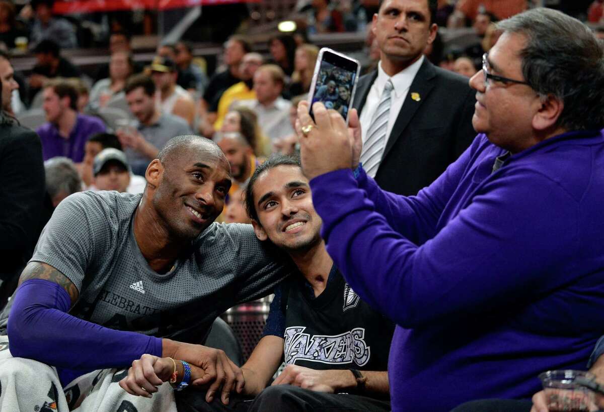 Los Angeles Lakers guard Kobe Bryant, left, poses for a photo with a fan during the first half of an NBA basketball game against the San Antonio Spurs, Saturday, Feb. 6, 2016, in San Antonio. (AP Photo/Darren Abate)