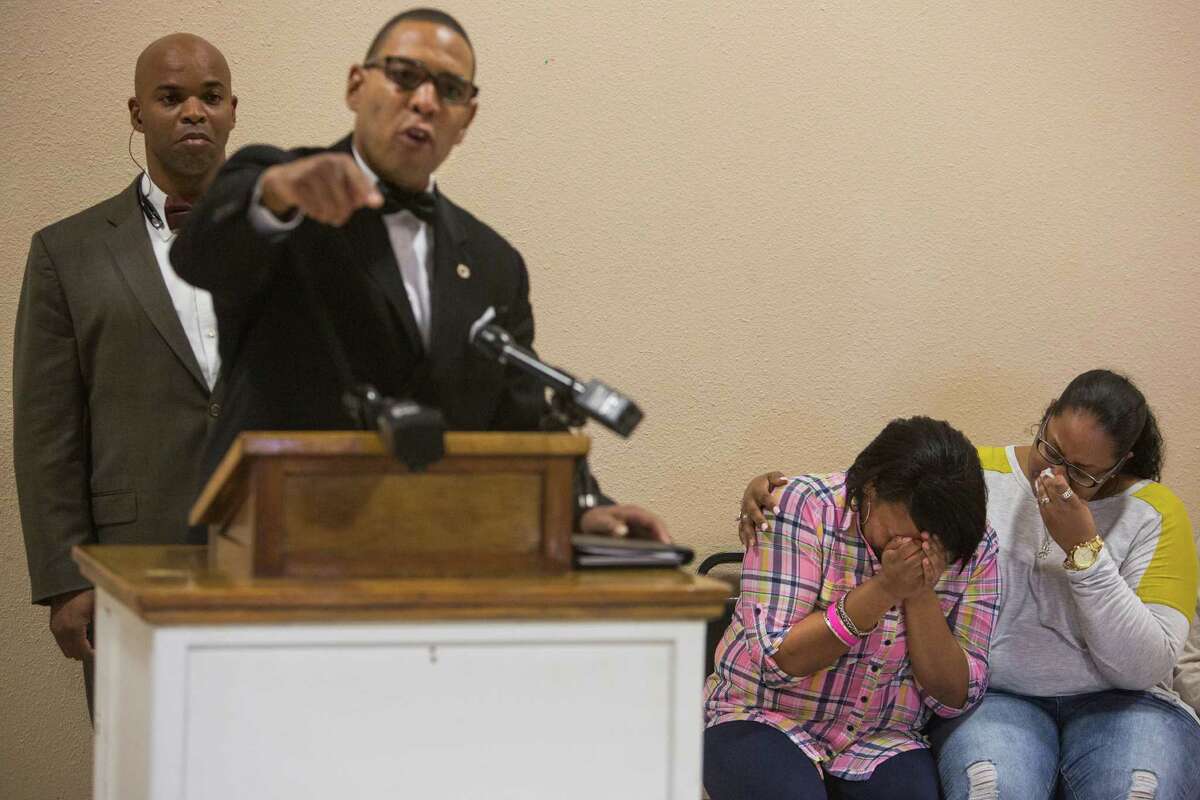 Terrence Coklow of the Greater East Side Coalition speaks at a news conference at the Barbara Jordan Community Center as Charissa Sprawling-Mickles (right) comforts her sister Elena Sprawling-Scott, the widow of Antronie Scott.