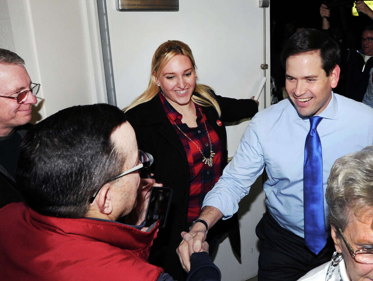 At center, Shelton native Elissa Voccola, the deputy New Hampshire director of U.S. Senator Marco Rubio’s Republican Presidential Primary campaign, holds a door for Rubio as the candidate greets supporters at the start of a Town Hall Meeting at the Mary Fisk Elementary School in Salem, N.H., on Thursday.