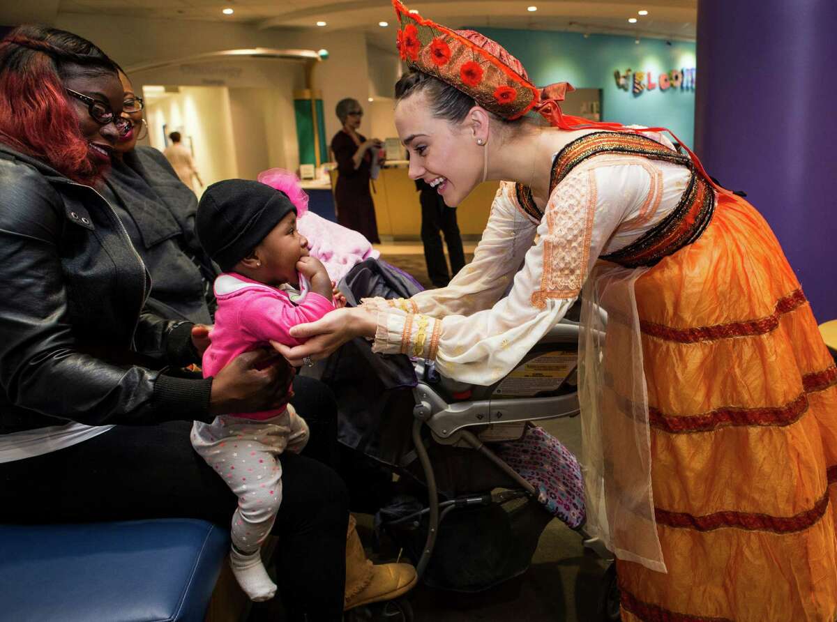 Emily Seymour, right, reaches out to embrace seven-month-old Techeria Murray, who is being held by her mother, Chantel Brambel, as members of Houston Ballet's production of The Sleeping Beauty visit patients Texas Children's Cancer and Hematology Centers on Monday, Feb. 8, 2016, in Houston.
