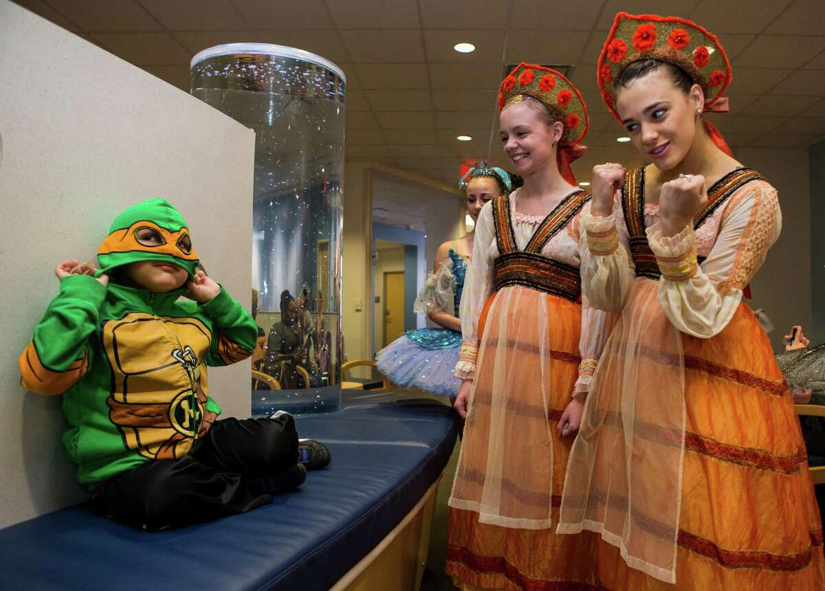 Kevin Bolton II puts a Ninja Turtle mask on as he is greeted by Katy Harvey, center, and Emily Seymour as members of Houston Ballet's production of The Sleeping Beauty make a special visit to patients Texas Children's Cancer and Hematology Centers on Monday, Feb. 8, 2016, in Houston.