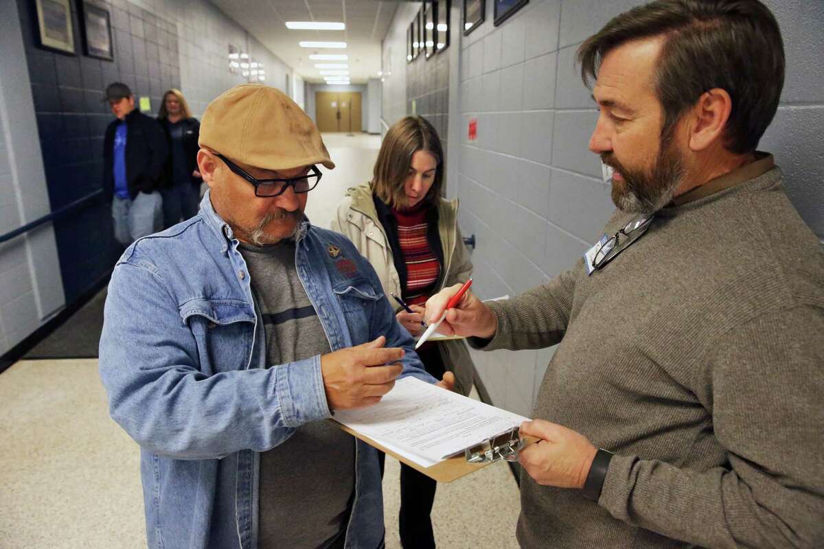 Tracy Crane (right) gets Bonifacio Lara and Rebecca Velez to sign a petition as citizens of the Oak Run subdivision gather for a town hall meeting with New Braunfels ISD and local government officials on February 4, 2016 at Oak Run Middle School concerning the proposed construction of a roadway through their neighborhood into the site of a new elementary school in the Veramendi development on the outskirts of town.