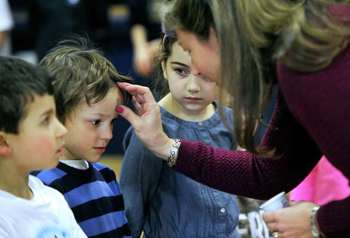 Above, Sean Ward receives ashes on his forehead from teacher assistant Janette Buonaiuto in observance of Ash Wednesday at St. Gregory the Great Catholic School in Danbury Wednesday as Gabriella Borges waits her turn.