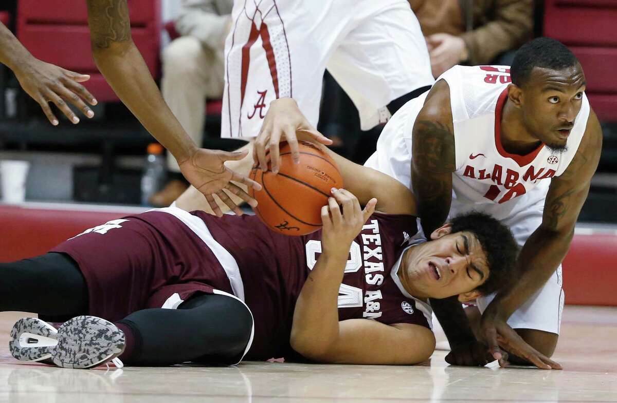 Texas A&M center Tyler Davis (34) and Alabama forward Jimmie Taylor (10) both dive for the ball during the first half of an NCAA college basketball game Wednesday, Feb. 10, 2016, in Tuscaloosa, Ala. Alabama won 63-62. (AP Photo/Brynn Anderson)