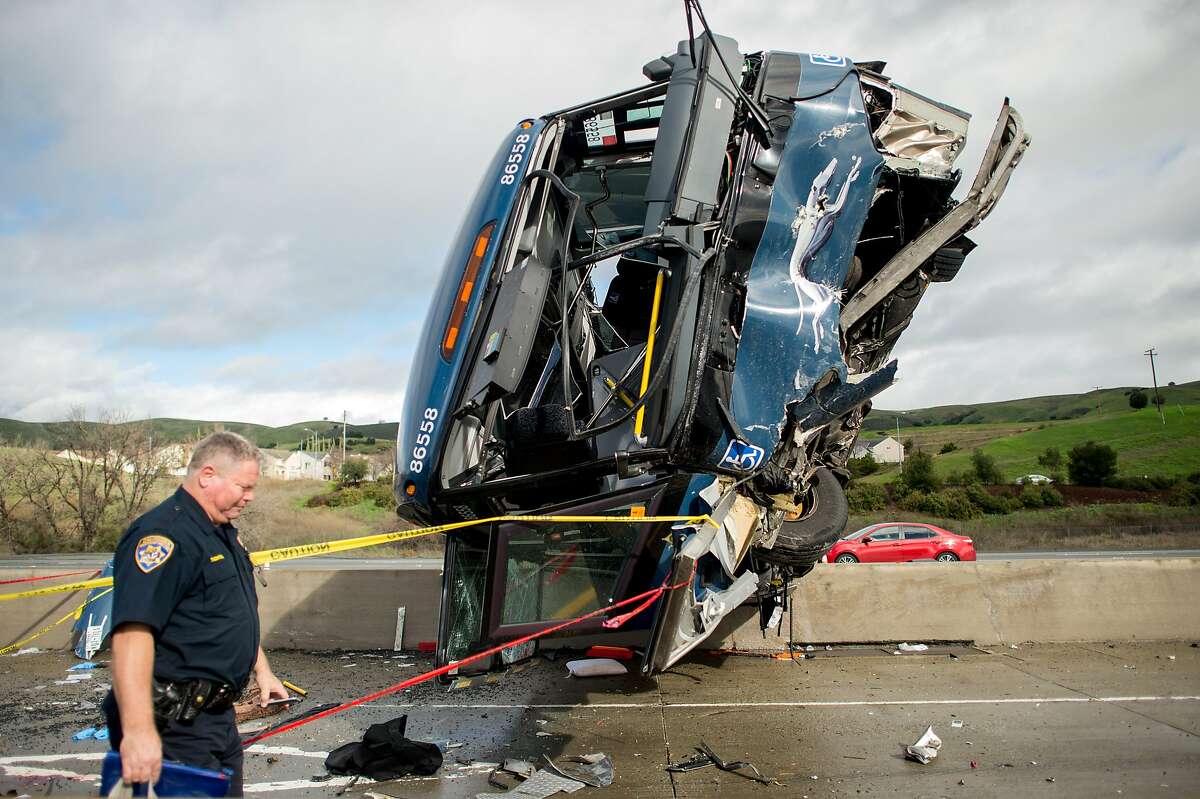 A California Highway Patrol officer moves belongings from a Greyhound bus crash that left two dead and at least eight injured on Tuesday, Jan. 19, 2016, in San Jose, Calif. A Greyhound spokeswoman said the bus, which left Los Angeles Monday night, was carrying 20 passengers in addition to the driver. (AP Photo/Noah Berger)
