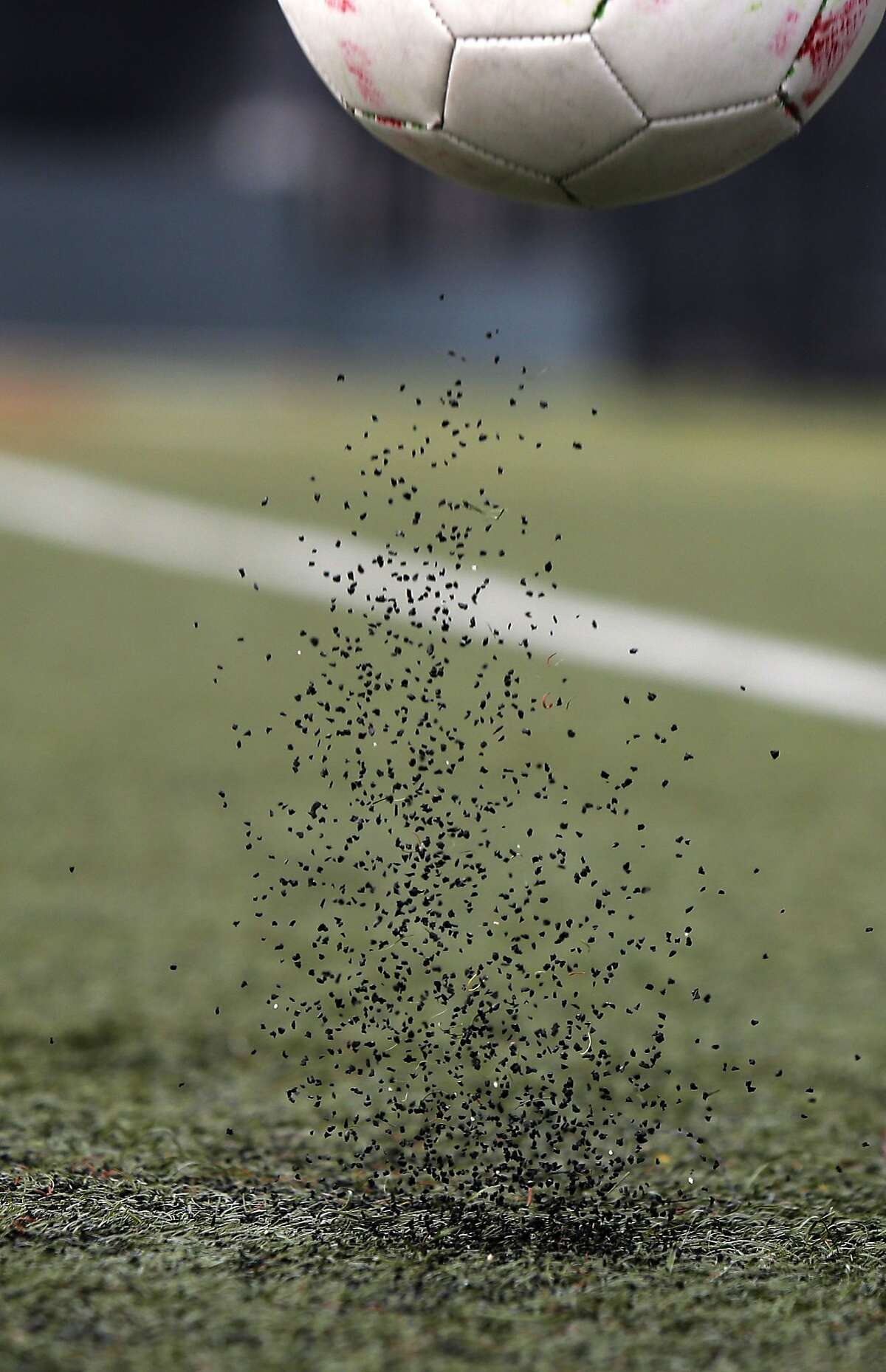 Kathleen McCowin bounces a soccer ball on the synthetic soccer field, at South Sunset Park, in San Francisco, Calif., to demonstrate the movement of the rubber material contained in the turf as seen on Fri. Jan. 16, 2015.