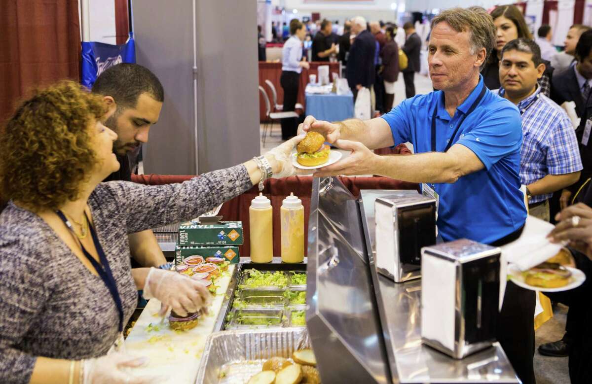 Esther Grosman, owner of a franchise in Dallas, serves a Burgerim mini hamburger to Steve Belko at the Franchise Expo South at the NGR Center.