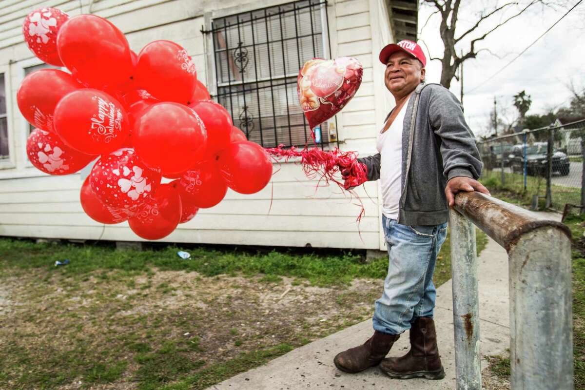 Alfredo Morales holds a bundle of red Valentine's balloons before as he waits to deliver them to family on Sunday, Feb. 14, 2016, in Houston.