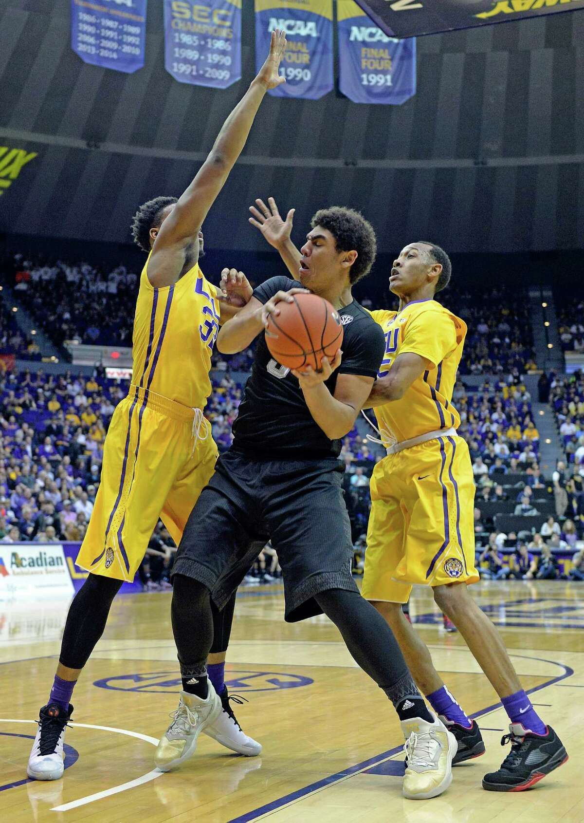 Texas A&M center Tyler Davis (34) is sandwiched by LSU forward Craig Victor II (32) and LSU guard Tim Quarterman, right, in the first half of an NCAA college basketball game in Baton Rouge, La., Saturday, Feb. 13, 2016. LSU won 76-71. (AP Photo/Bill Feig)