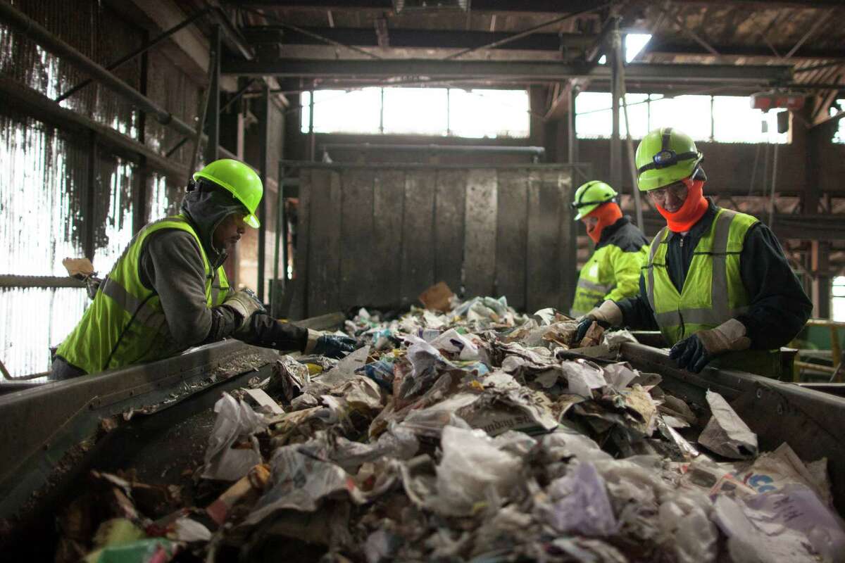 In 2017, a Pearland employee was hospitalized after suffering from "dehydration and heat illness while on a trash collection route," according to OSHA records. Pictured: Workers remove contaminants from a stream of recyclables at the Waste Management facility in Newark, N.J.