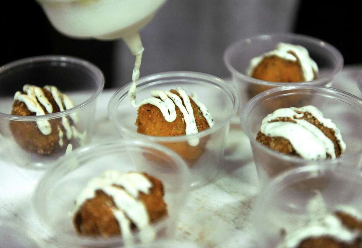 Brooke Taney of Slidin' Dirty puts a touch of cilantro cream on her chipotle cream cheese poppers, called Great Balls of Fire, during the Mac-n-Cheese Bowl on Saturday, Feb. 21, 2015, at Siena College in Loudonville, N.Y. (Cindy Schultz / Times Union) ORG XMIT: MER2015022117003458