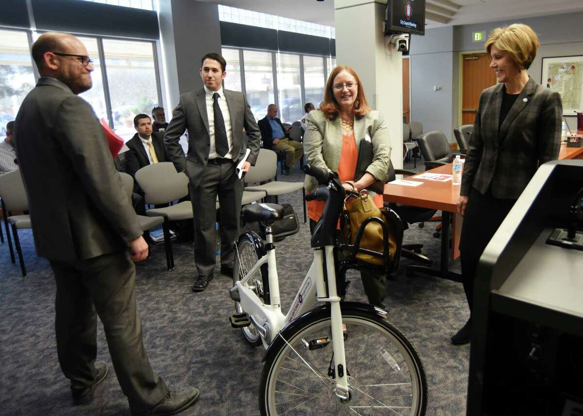 Douglas Melnick, left, the city’s chief sustainability officer, and JD Simpson, second from right, executive director of the nonprofit San Antonio Bike Share, show the new B-Cycle 2.0 to City Manager Sheryl Sculley before a meeting with the San Antonio City Council on Wednesday. B-Cycle, the city's bike sharing program, is adding three new stations at The Pearl, San Antonio College and the DoSeum. It also plans to introduce 50 of the newer, sleeker bikes in April.