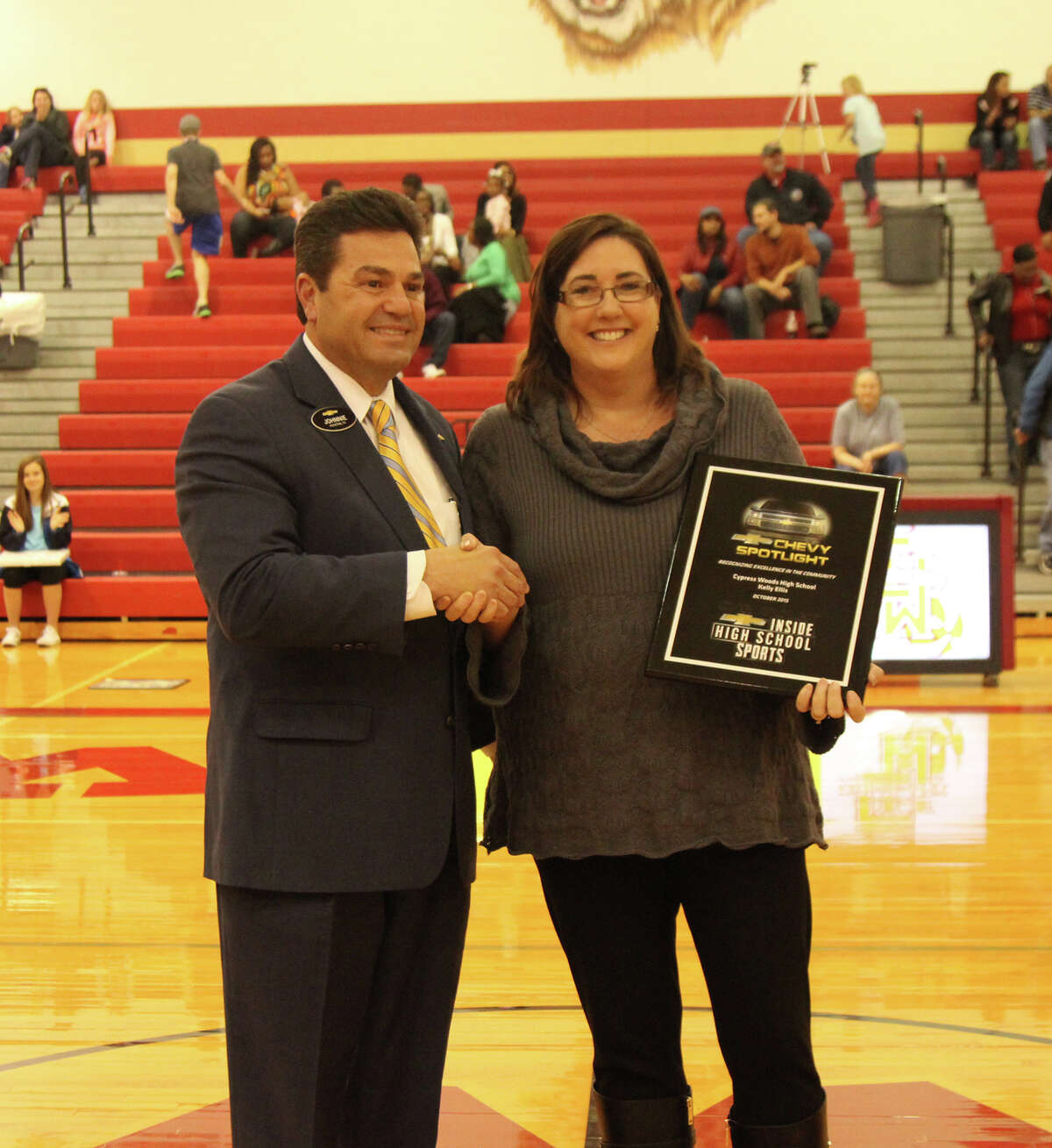 Johnnie Smith, general manager for Lone Star Chevrolet, presents the Chevrolet Spotlight Award to Cypress Woods High School director of instruction Kelly Ellis Feb. 5 at the Lady Wildcats' basketball game.