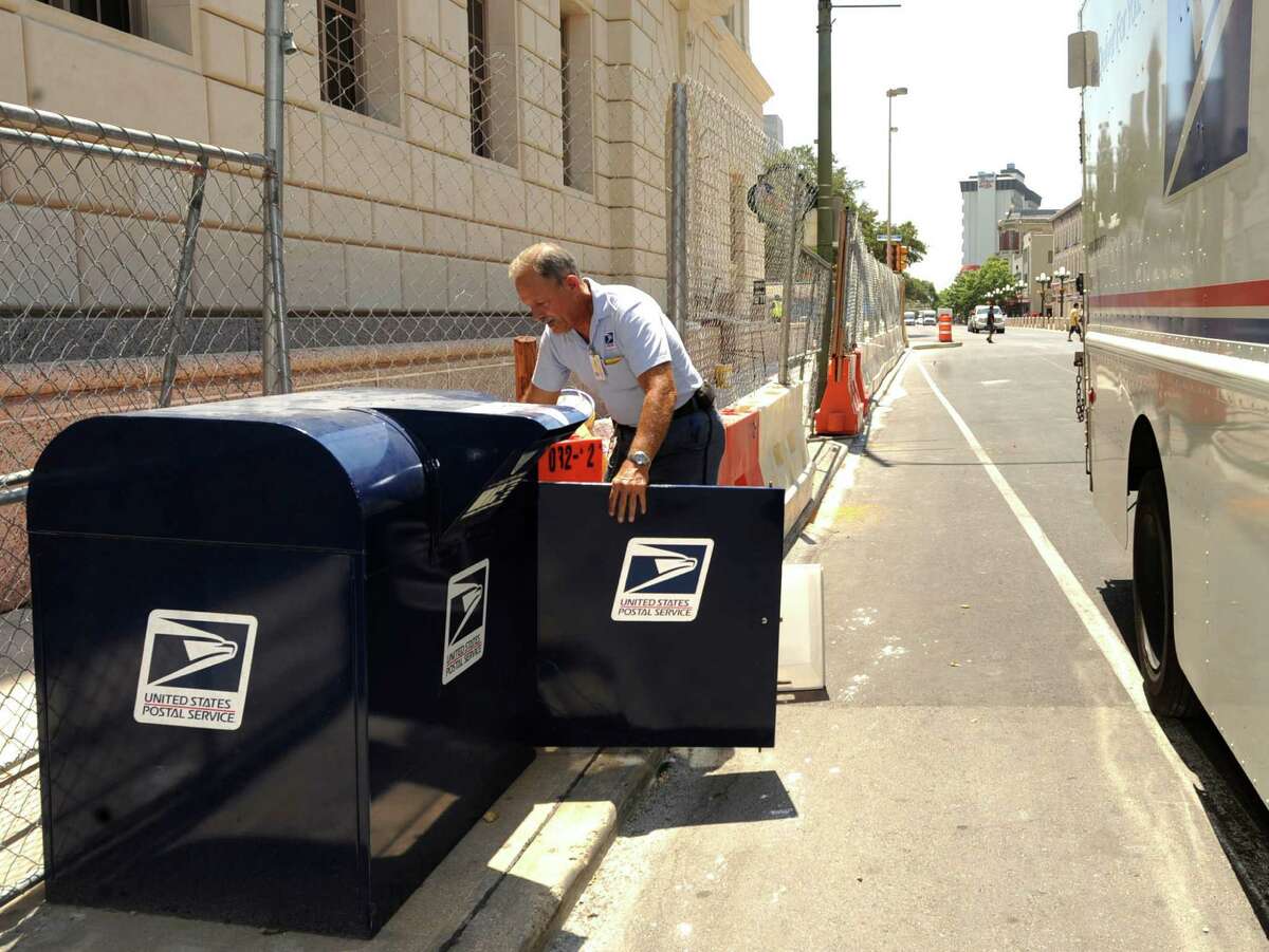 A U.S. Postal Service employee collects mail from a box on South Alamo Street at the downtown post office in this 2011 file photo.