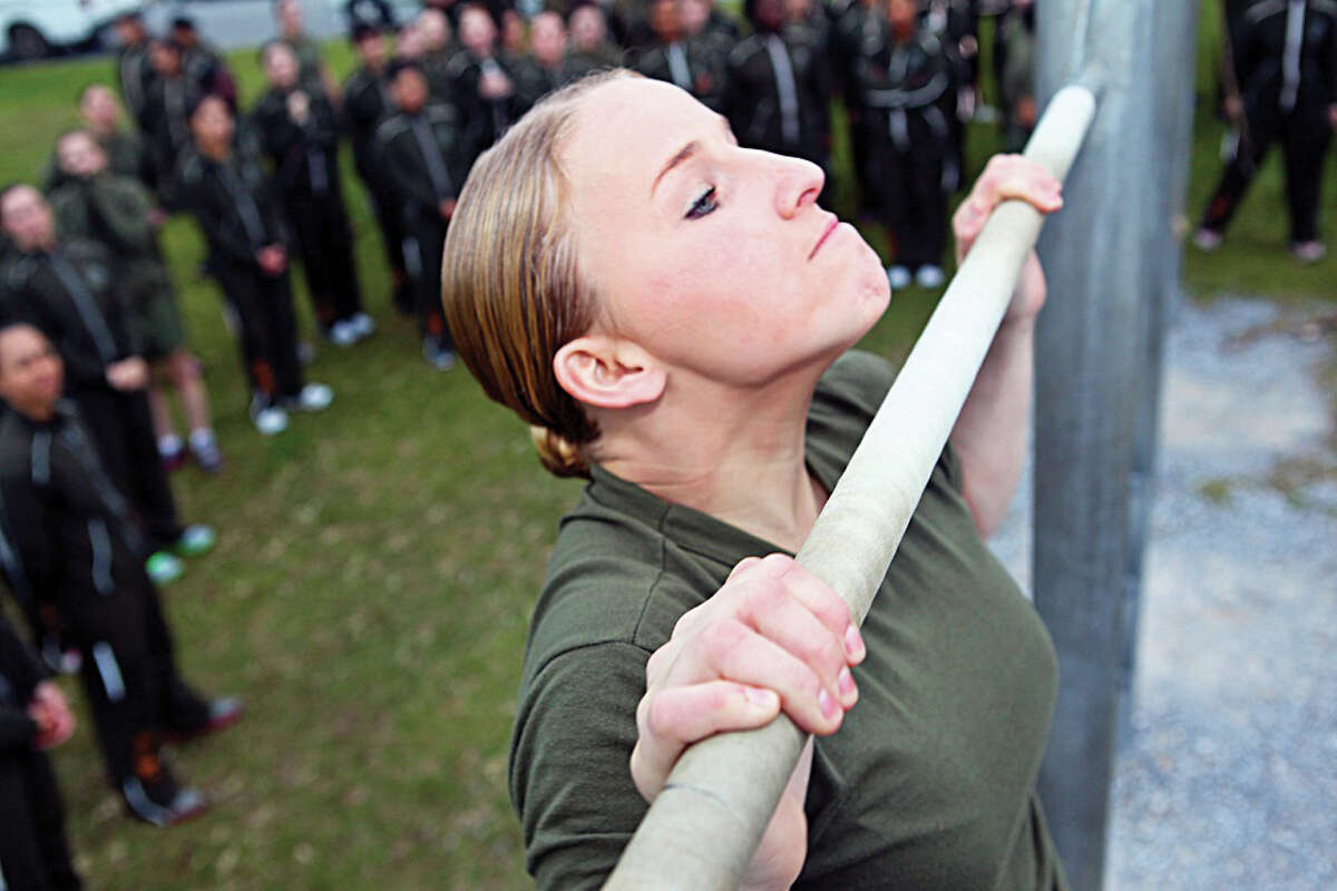 Lance Cpl. Katelyn Hunter does pull-ups at Camp Foster in Japan. As the Pentagon grapples with how to integrate women into all jobs in combat, a new proposal has surfaced: whether to require them to register for the draft as do young men.