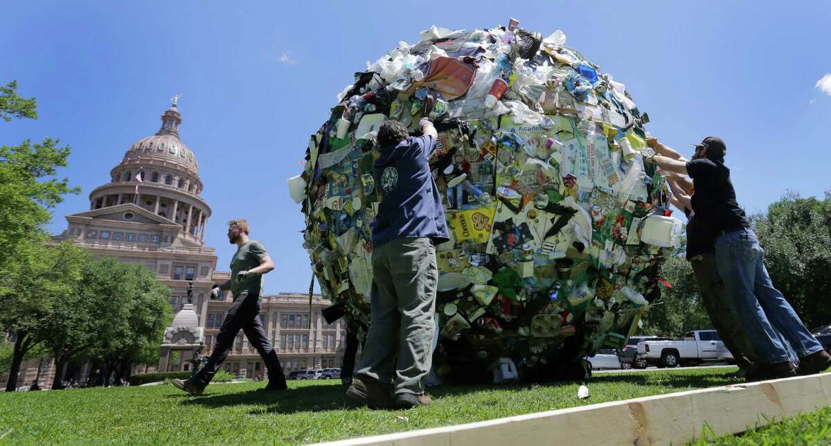 Workers remove a large ball of trash from the lawn of the Texas Capitol, Wednesday, April 29, 2015, in Austin, Texas. The ball of trash was used as a prop by the Texas Department of Transportation to launch new announcements as part of the "Don't mess with Texas" anti-litter campaign.