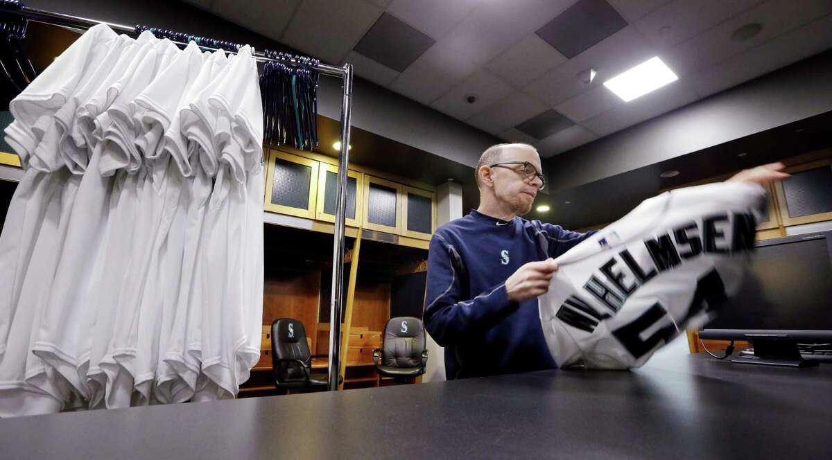 Seattle Mariners clubhouse assistant Pete Fortune begins to fold a jersey of former relief pitcher Tom Wilhelmsen, who was traded to the Texas Rangers, as he packs equipment bound for spring training, Wednesday, Feb. 10, 2016, in Seattle. Because the white jerseys are only used for photo day, outdated jerseys can be re-used. Fortune, a 30-year team employee, said the turnover of players on the club from the previous season is the most that he recalls ever seeing. Team personnel loaded a moving van with baseball gear Wednesday morning to be shipped to the team's training facility in Peoria, Ariz. Pitchers and catchers begin working out Feb. 20. Position players begin the first full squad workout Feb. 25. (AP Photo/Elaine Thompson)