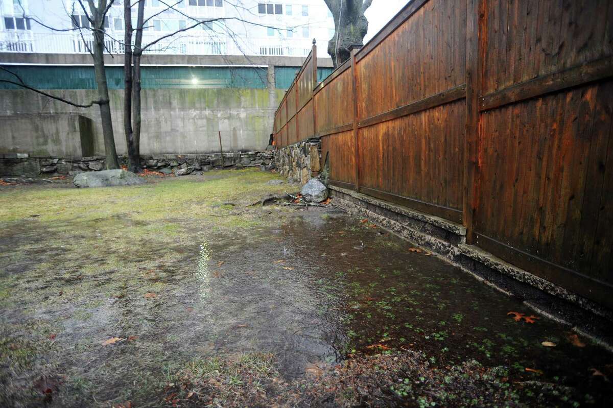 During heavy rain Stamford resident Stella Horton's Hillandale Ave. backyard consistently floods, creating small pools of water while soaking the rest of the yard. Ms. Horton blames the high rise apartment complex behind her, saying water runs off the parking garage and down the tall concrete wall onto her property. Photographed on Tuesday, Feb. 16, 2016.