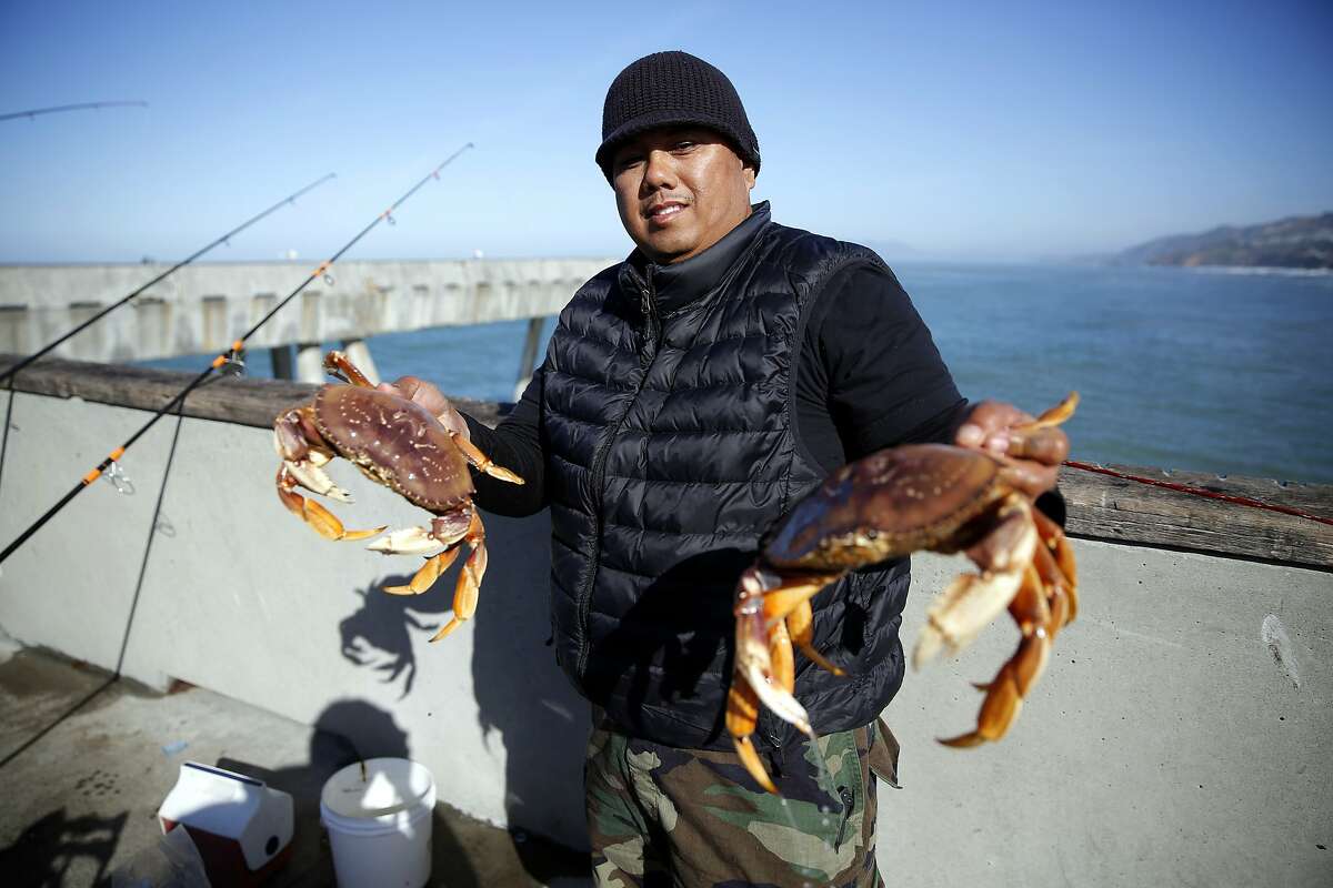 Jimmy Narag holds two of the crabs he caught off Pacifica Municipal Pier in Pacifica on Sunday, Feb. 21.