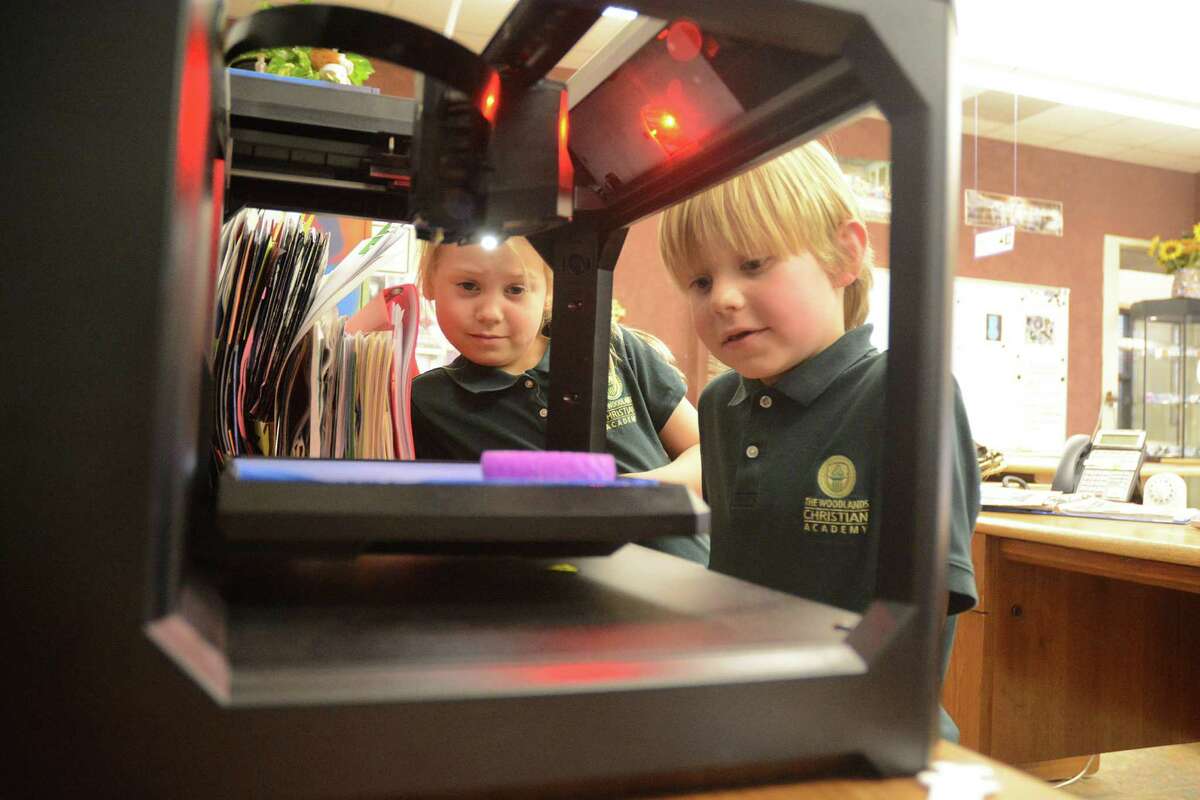 First graders Avery Rook and Banner Carlson watch a 3D printer produce an art project at The Woodlands Christian Academy.