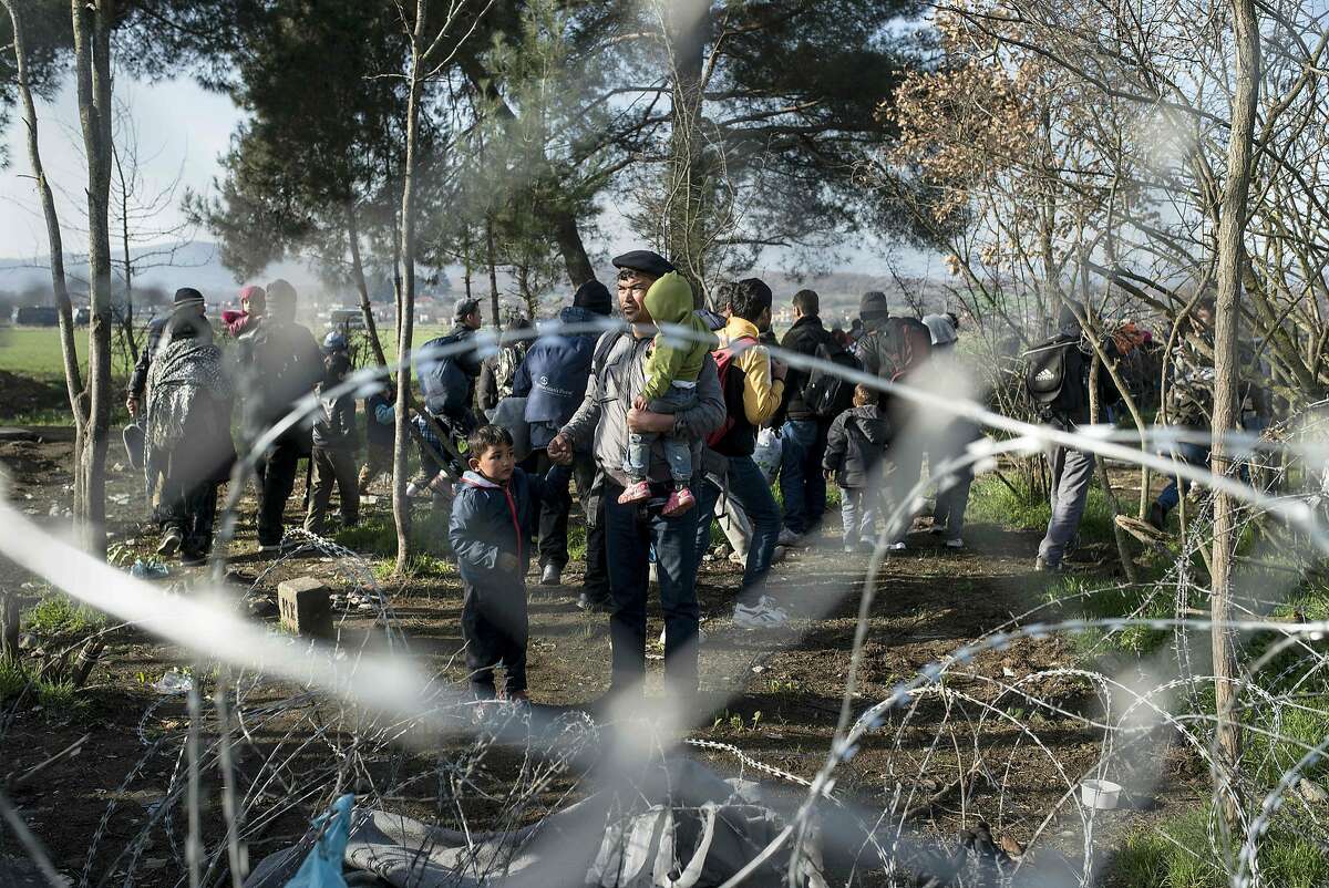 TOPSHOT - A photo taken from the Macedonian side of the border shows Afghan migrants fleeing the Greek police alongside the wired fence on the Macedonian-Greek border near Gevgelija on February 23, 2016. Greece said on February 22 that it was taking action to persuade Macedonia to take in Afghan migrants as thousands remained stranded at the border and the main port in Athens. About 5,000 refugees and migrants are stuck at the border with Macedonia after the neighbouring non-EU state on February 21 refused to allow passage to Afghans, police said.