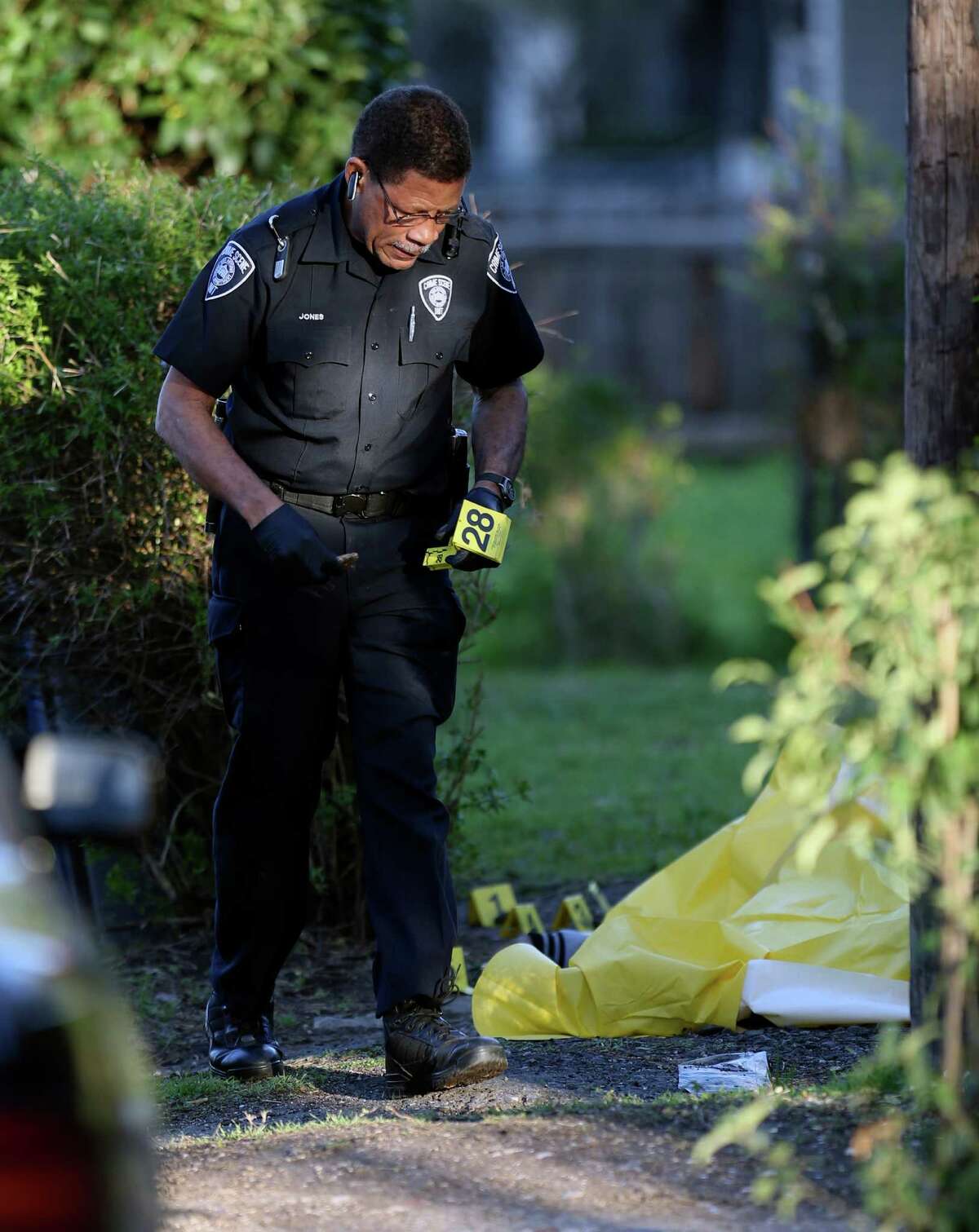 An evidence technician places evidence markers Tuesday afternoon, Feb. 22, 2016 near the body of a shooting victim in the 300 block of Belmont. Three people were shot in the incident that police described as a shootout. One person died at the scene. One person was transported to SAMMC from the scene. The third victim was found near Houston and Lasoya before being transported to SAMMC. Both injured victims were in critical condition, police said.