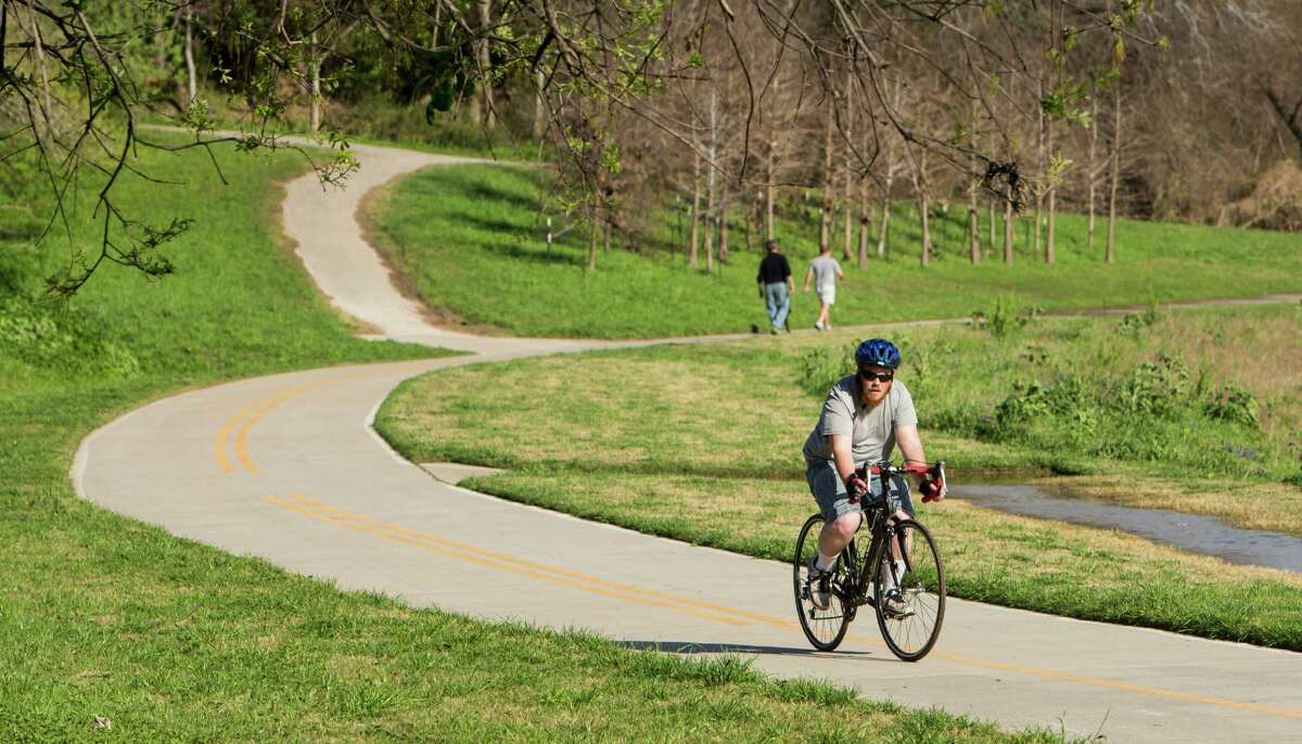 A cyclist uses a trail next to White Oak Bayou. Many of Houston's current bike trails are not connected.﻿