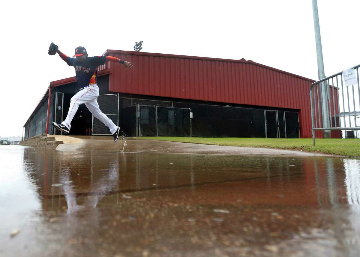 Houston Astros bullpen catcher Carlos Munoz leaps over a large puddle outside of the batting cages, as players worked out inside due to the rain at the Astros spring training in Kissimmee, Florida, Wednesday, Feb. 24, 2016.