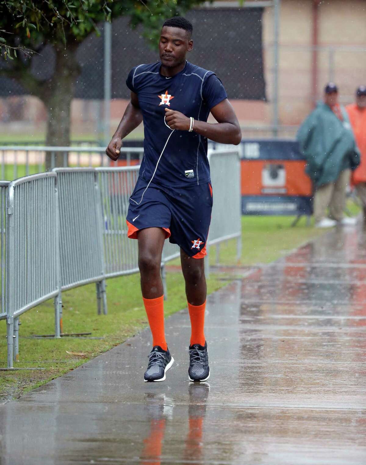 Houston Astros pitcher David Paulino runs through a rain shower to get to an exercise room during a spring training baseball workout, Wednesday, Feb. 24, 2016, in Kissimmee, Fla. (AP Photo/John Raoux)
