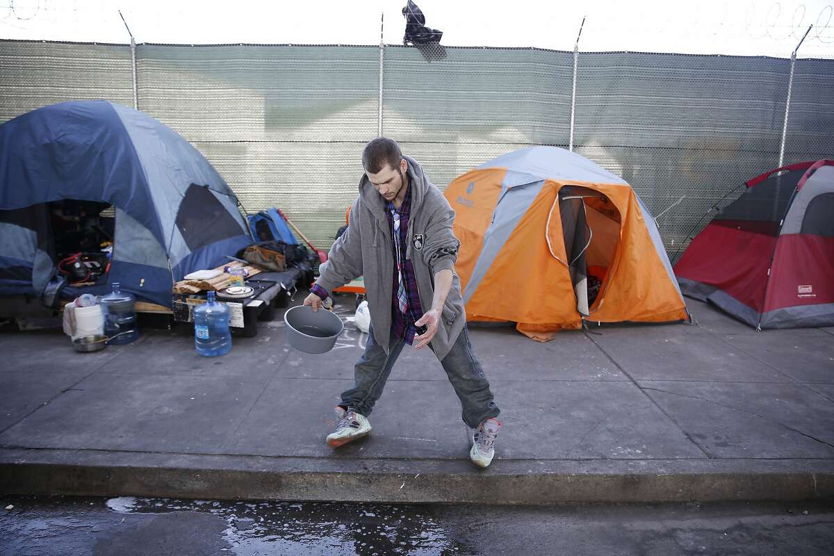 Jeremy Harrell, homeless resident, rinses a wound with water from a bin after washing it to prevent infection along 13th Street on Wednesday, February 24, 2016 in San Francisco, California.