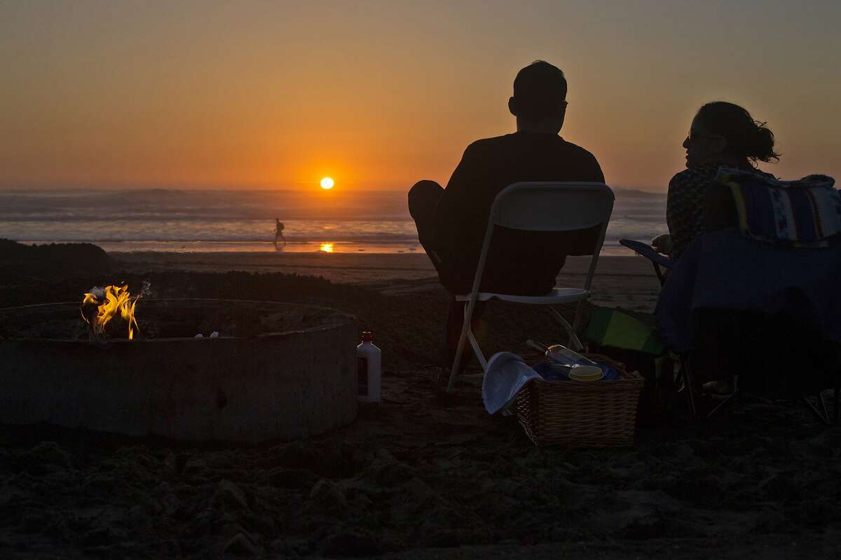 Jacob Larin of San Francisco, and Elise Harb, of Oakland, watch the sun set next to their fire pit on Ocean Beach on Wednesday, February 24, 2016 in San Francisco, Calif.