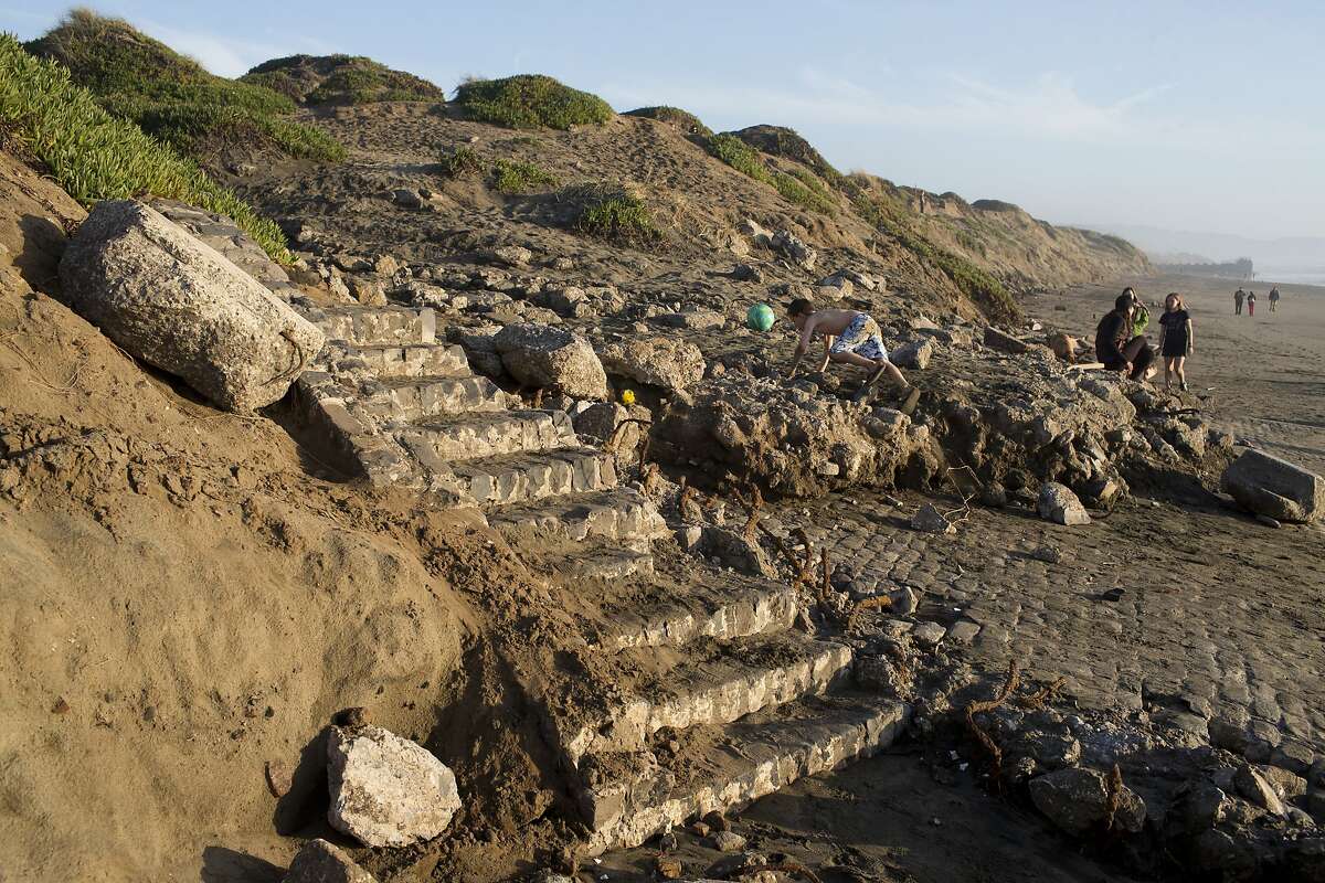 Beach-goers walk down the unearthed cobble-stone stairs and seawall near Taraval Street on Ocean Beach on Wednesday, February 24, 2016 in San Francisco, Calif.