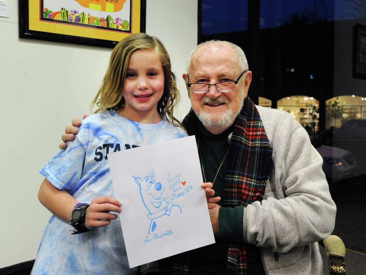 At right, Ron Campbell, an acclaimed cartoonist, with Katie Benincasa, 7, of Greenwich, holding the cartoon dog Scooby-Doo that he drew for her during an appearance to support his show at the C. Parker Gallery in Greenwich, Conn., Thursday night, Feb. 25, 2016. Campbell worked on major projects like Yellow Submarine and the Beatles Saturday morning cartoon show as well as cartoons like Scooby Doo, The Flintstones and Rugrats.