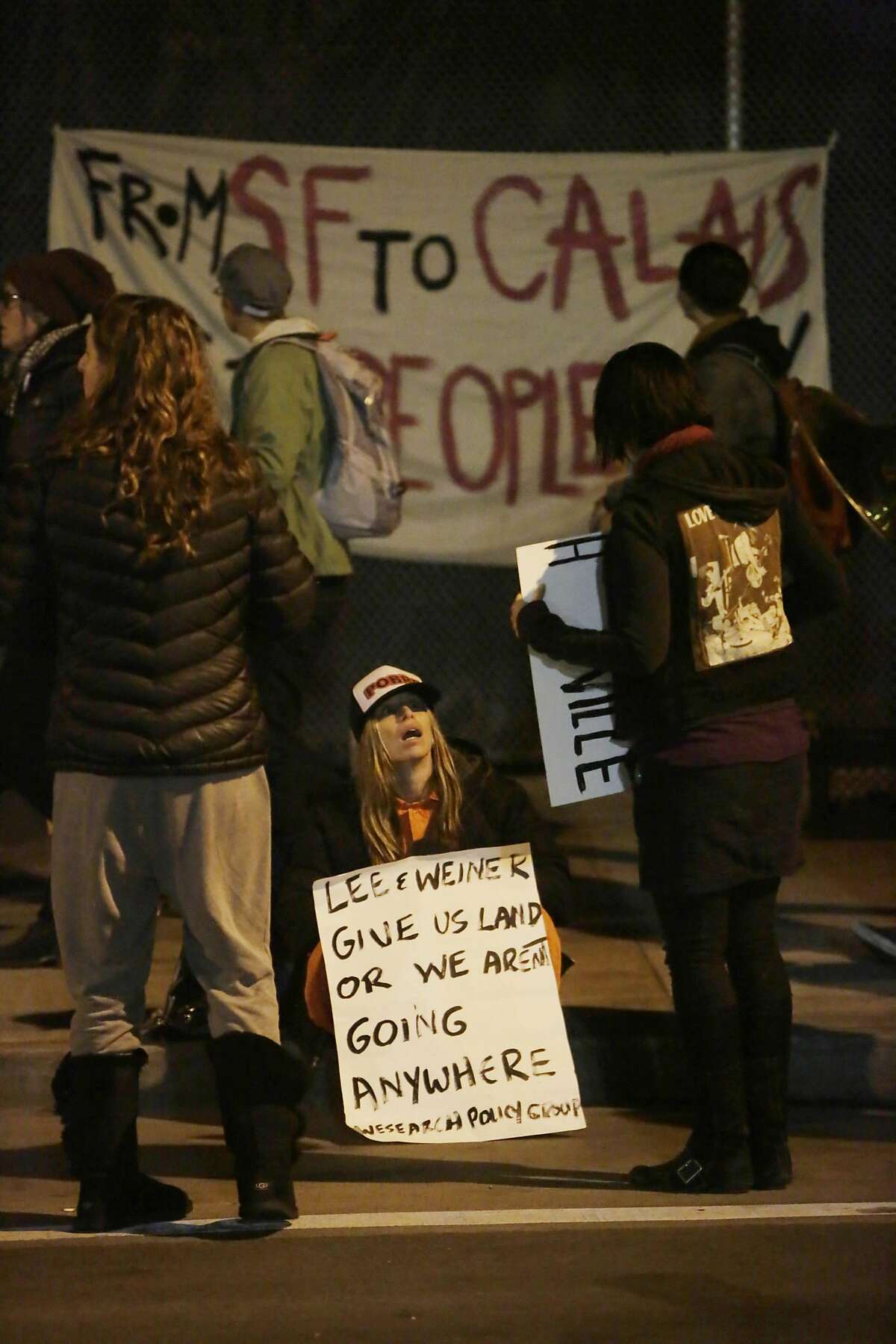 Homeless supporters hold signs along 13th Street during a vigil in the early morning on Friday, February 26, 2016 in San Francisco, California.