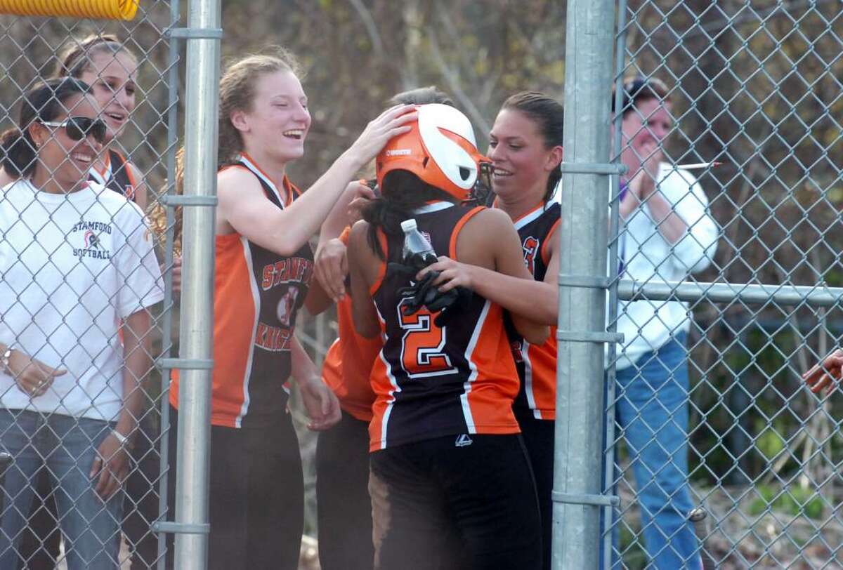 Stamford's Brittany Ulloa is celebrates with teammates Clare Kapinski, left, and Chelsea Sciarretta after scoring during OT as Trinity Catholic hosts Stamford High in a girls softball game Wednesday afternoon, April 7, 2010.