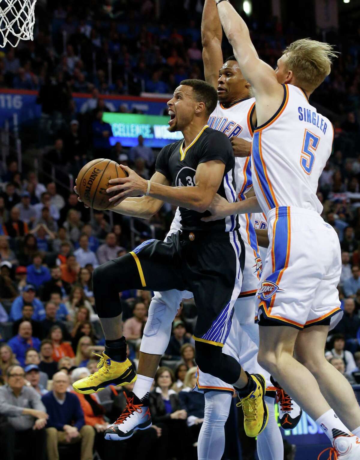 Golden State Warriors guard Stephen Curry, left, goes up for a shot in front of Oklahoma City Thunder forward Kevin Durant, center, and forward Kyle Singler (5) during the first quarter of an NBA basketball game in Oklahoma City, Saturday, Feb. 27, 2016. (AP Photo/Sue Ogrocki)