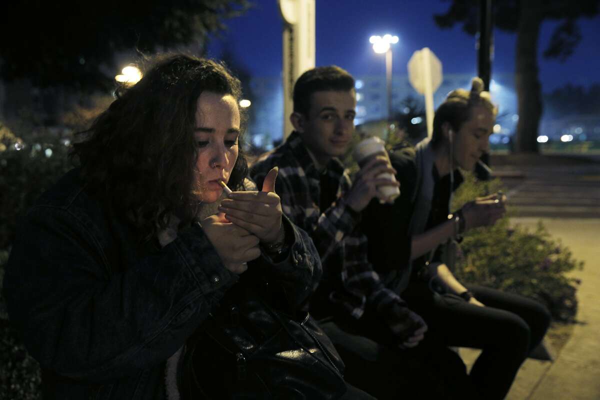 Natalie Richards, 19, smokes a cigarette as she sits with her friends Ben Rose, center, and Chase Melich, right, in a Designated Smoking Area at San Francisco State University as supervisors consider a plan to raise the purchasing age for tobacco products to 21 in San Francisco, Calif., on Monday, February 29, 2016.