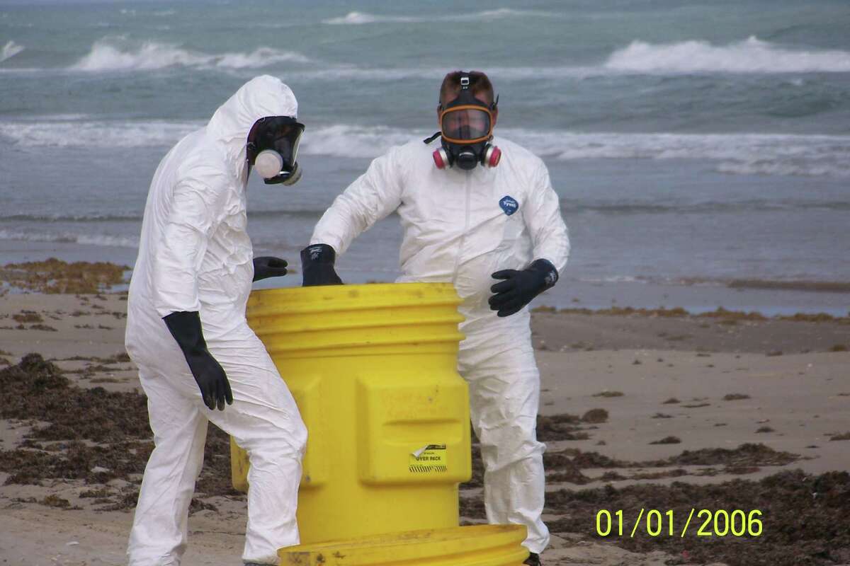 Workers in hazmat suits remove hazardous waste that washed up on Padre Island.