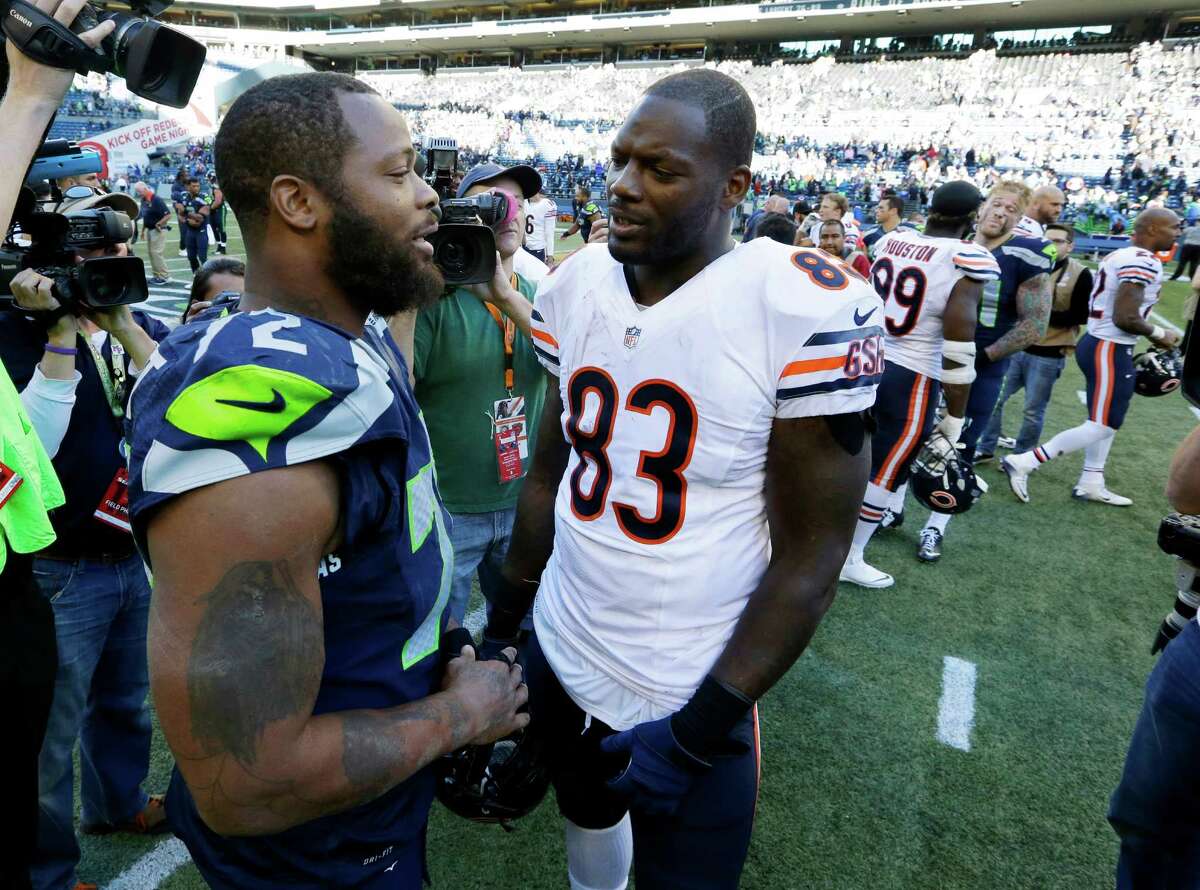 Seattle Seahawks defensive end Michael Bennett, left, talks with his brother, Chicago Bears tight end Martellus Bennett, right, after an NFL football game, Sunday, Sept. 27, 2015, in Seattle.