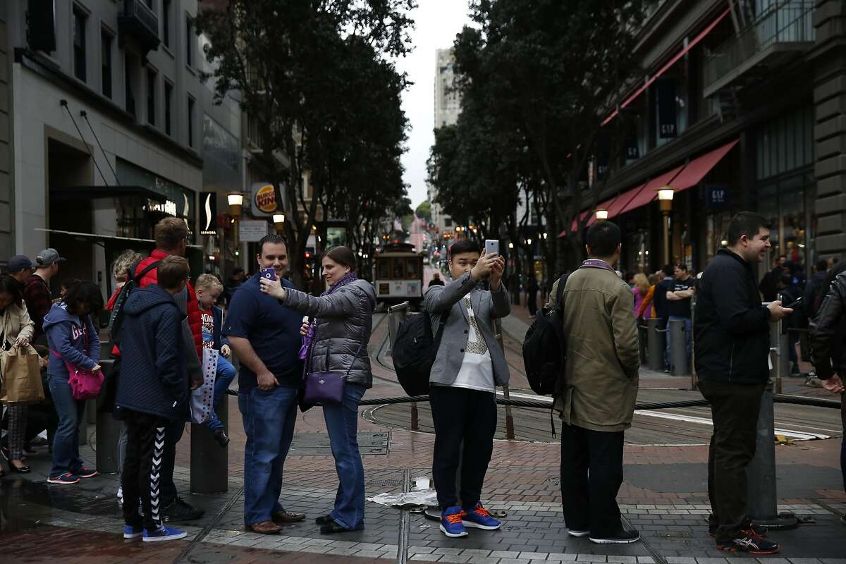 People take selfies while waiting for a cable car on Powell street March 3, 2016 in San Francisco, Calif.