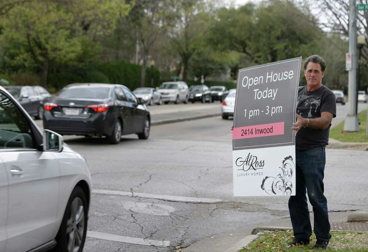 Ken McDermogg displays a sign at the corner of San Felipe and Kirby advertising an open house on Feb. 28. Luxury home sales are falling, and sellers are resorting to unusual tactics to hawk their properties.